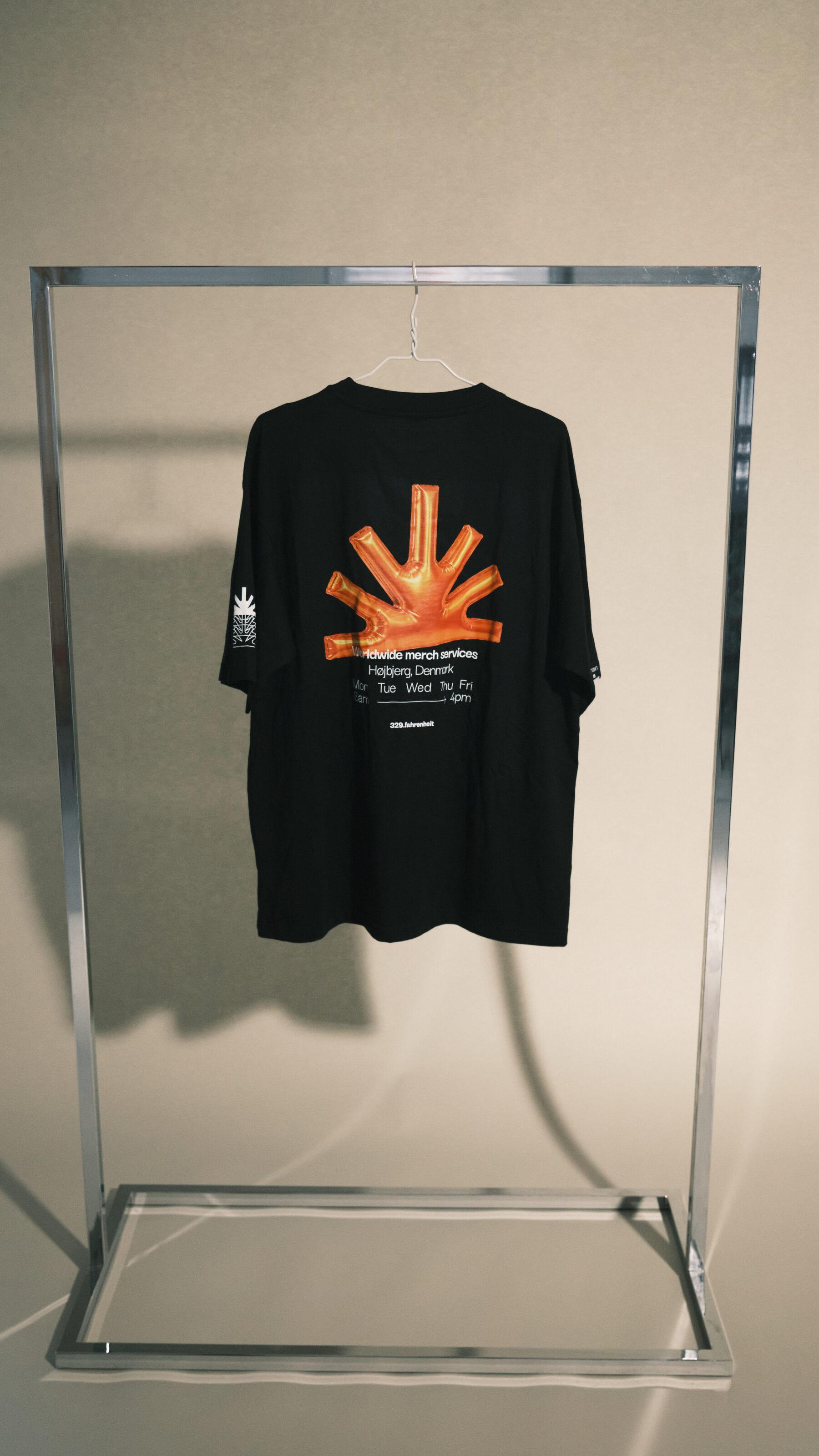 Sort t-shirt med orange tryk på ryggen, hængt op i et stålstativ