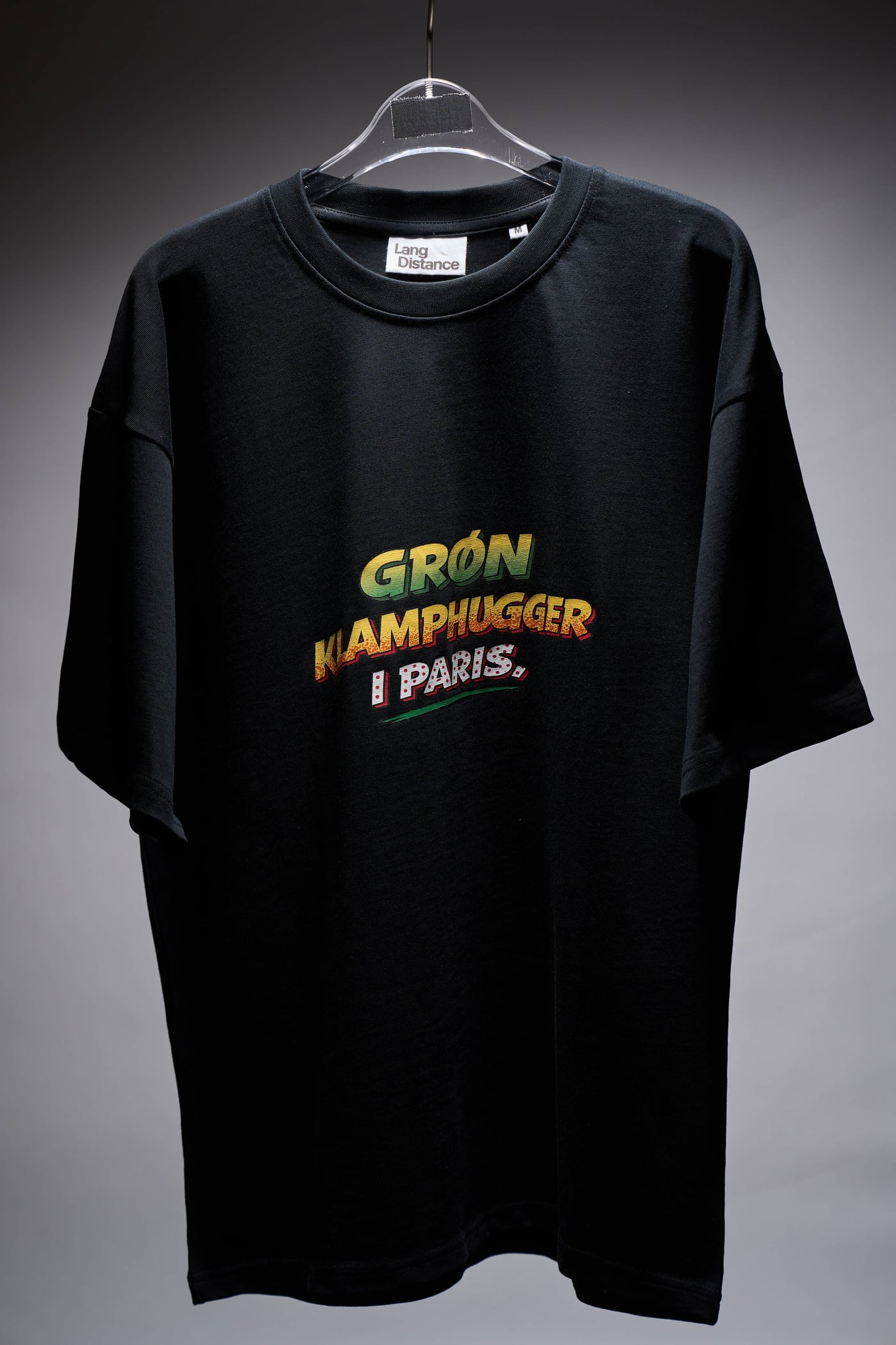 Sort oversize t-shirt på bøjle med trykket GRØN KLAMPHUGGER I PARIS i grønt, gult og rødt
