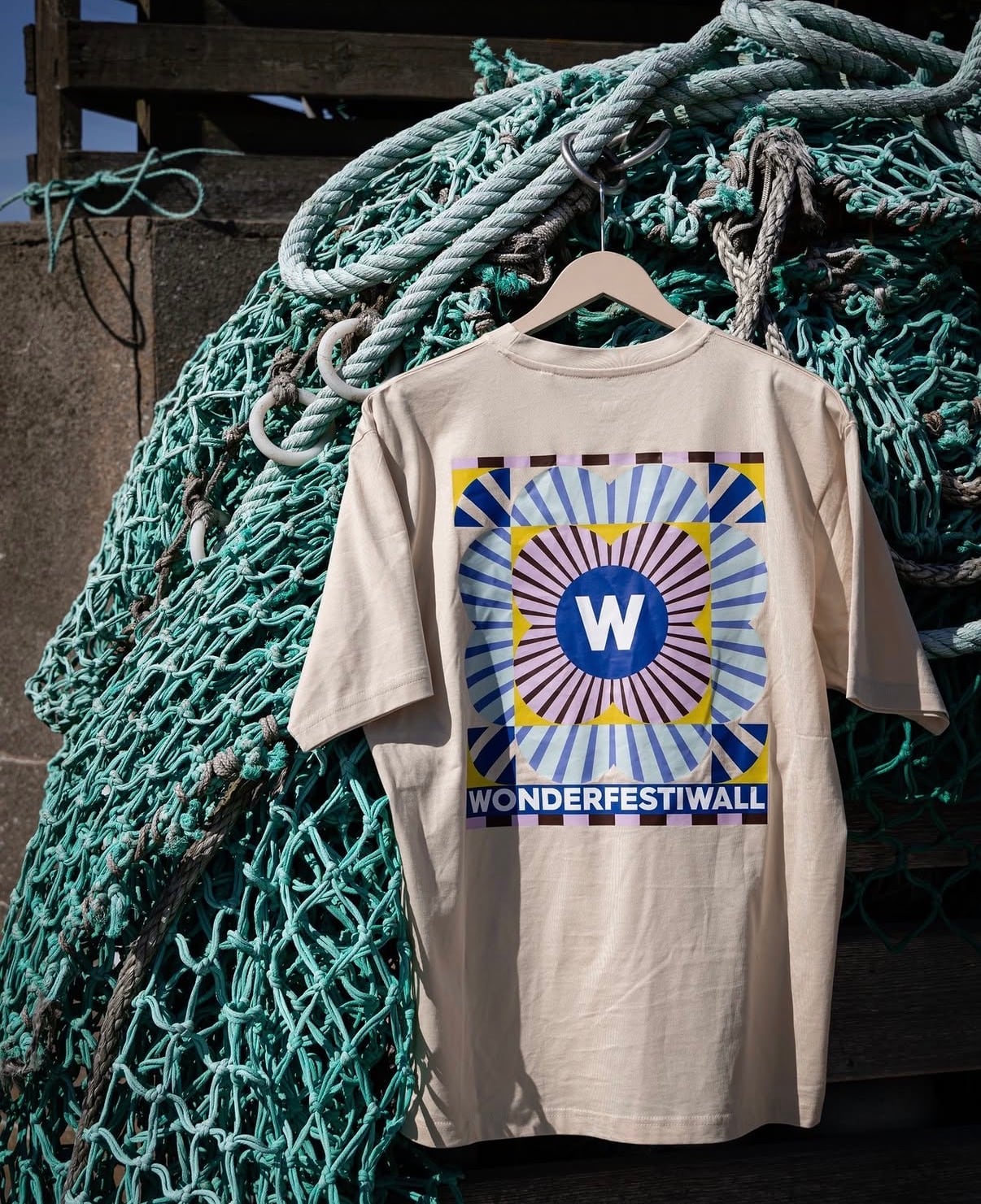 T-shirt med Wonderfestiwall-tryk hængt op i et grønt fiskenet
